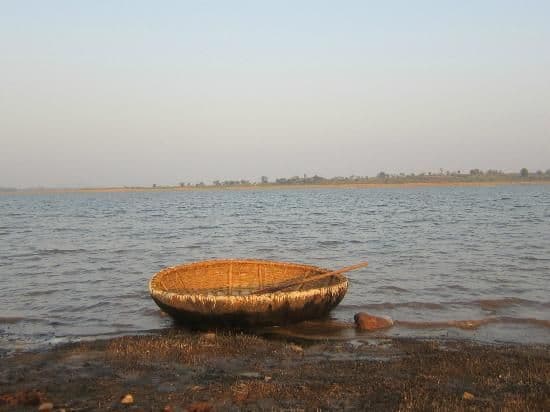 A traditional circular coracle boat floating on the peaceful waters of Kabini
